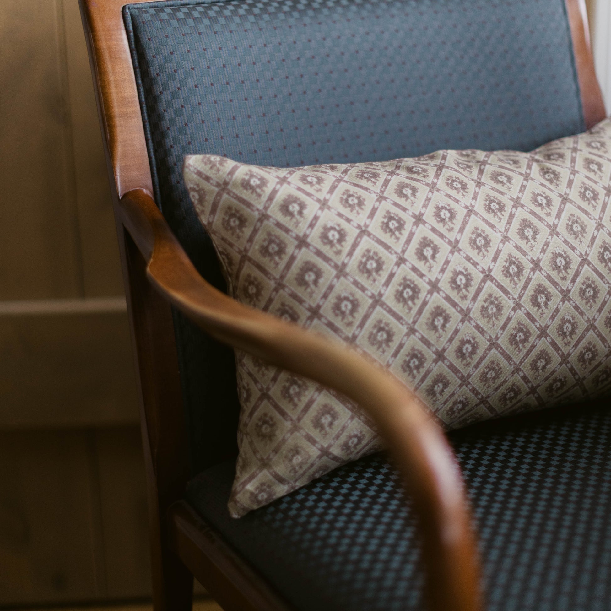 Noa lumbar pillow with geometric pattern in taupe and cream, displayed on a mid-century chair.