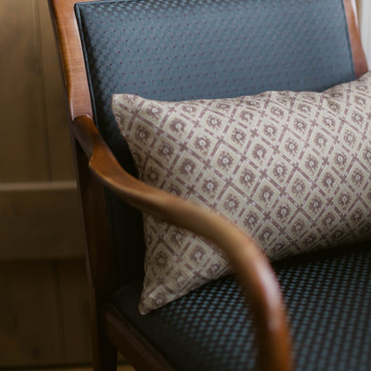 Noa lumbar pillow with geometric pattern in taupe and cream, displayed on a mid-century chair.