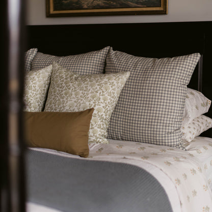 Gray and white gingham linen pillow displayed on a bed with coordinating patterned pillows.