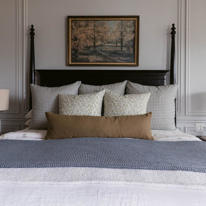 Rectangular lumbar pillow in solid moss green displayed on a bedroom bed with gingham and patterned pillows.