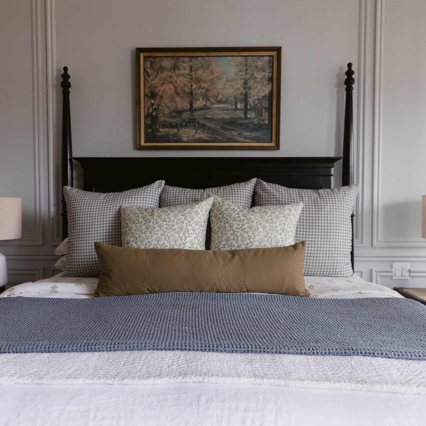 Moss Basics lumbar pillow in sage green displayed on bed with gingham and floral pillows.
