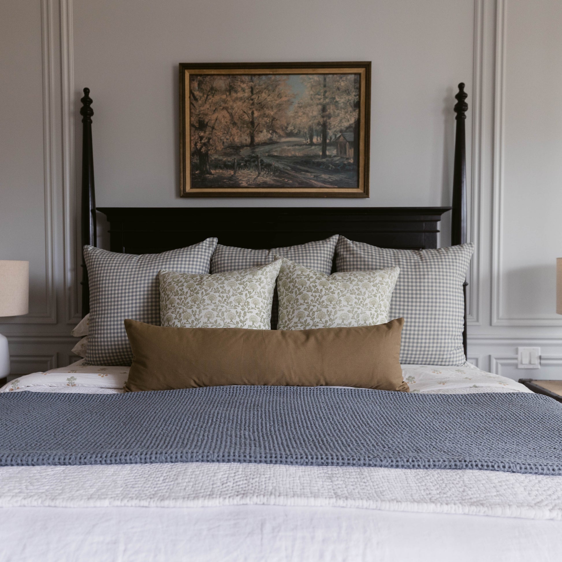 Moss Basics lumbar pillow in sage green displayed on bed with gingham and floral pillows.