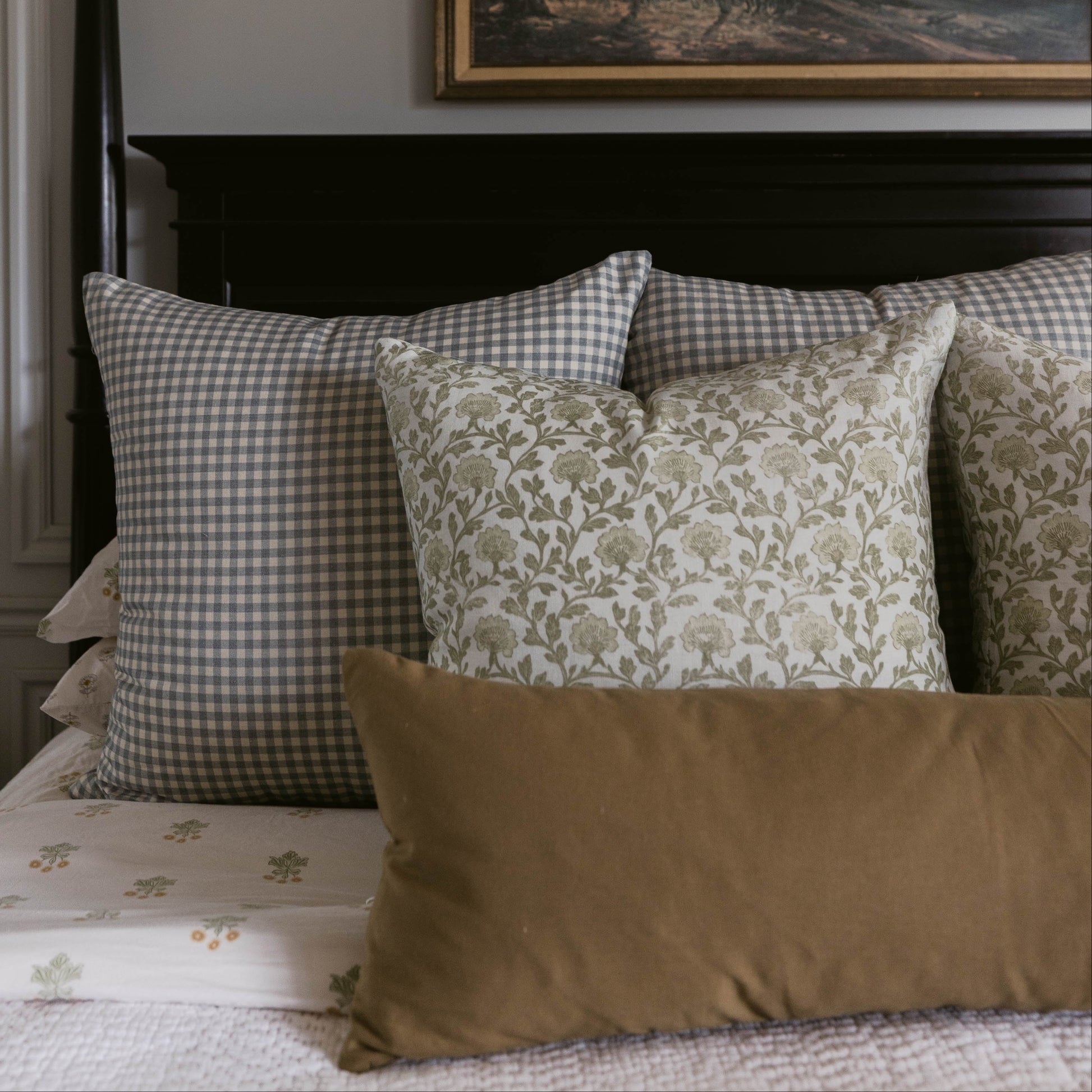 Linen pillow with gingham check pattern in gray and white, displayed on a bed with coordinating decorative pillows.