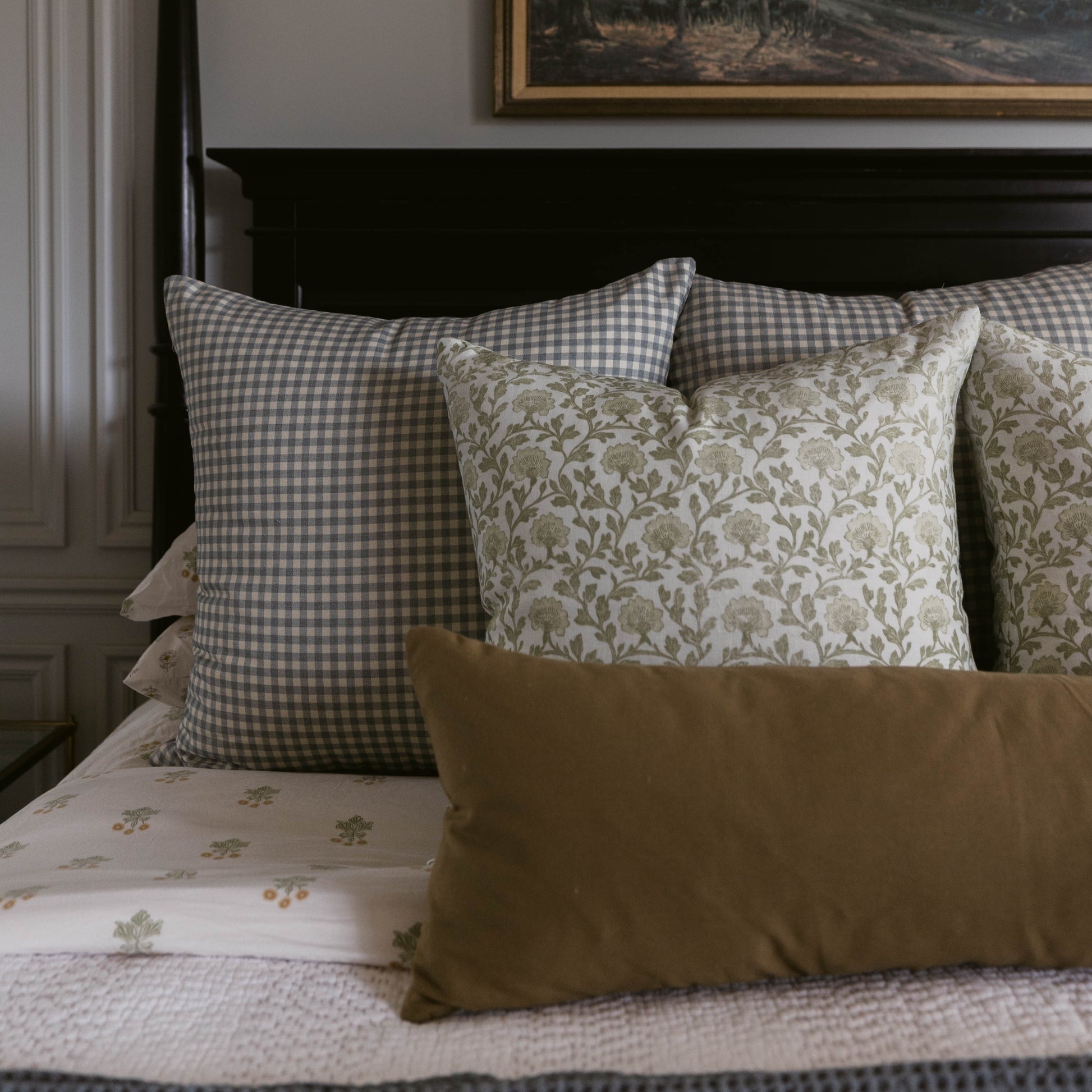 Gray and white gingham lumbar pillow displayed on bed with patterned and solid decorative pillows.