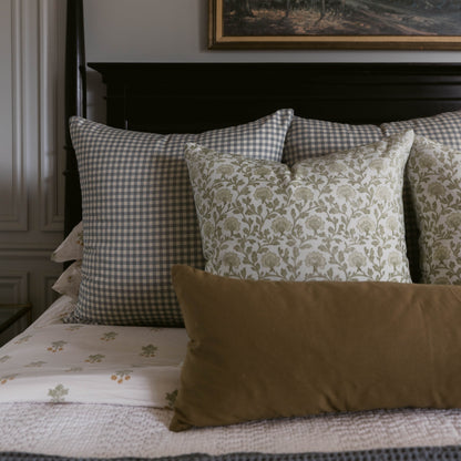 Gray and white gingham lumbar pillow displayed on bed with patterned and solid decorative pillows.