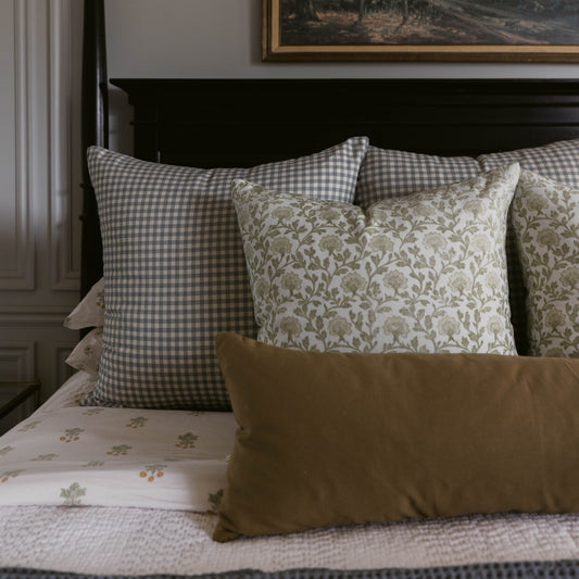 Gray and white gingham lumbar pillow displayed on bed with patterned and solid decorative pillows.