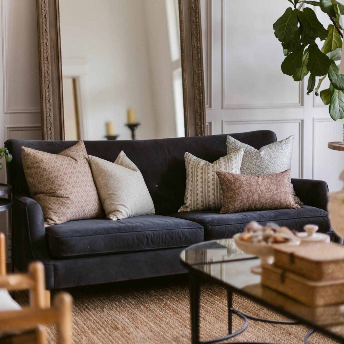 Black sofa with beige and taupe patterned throw pillows in a living room setting.