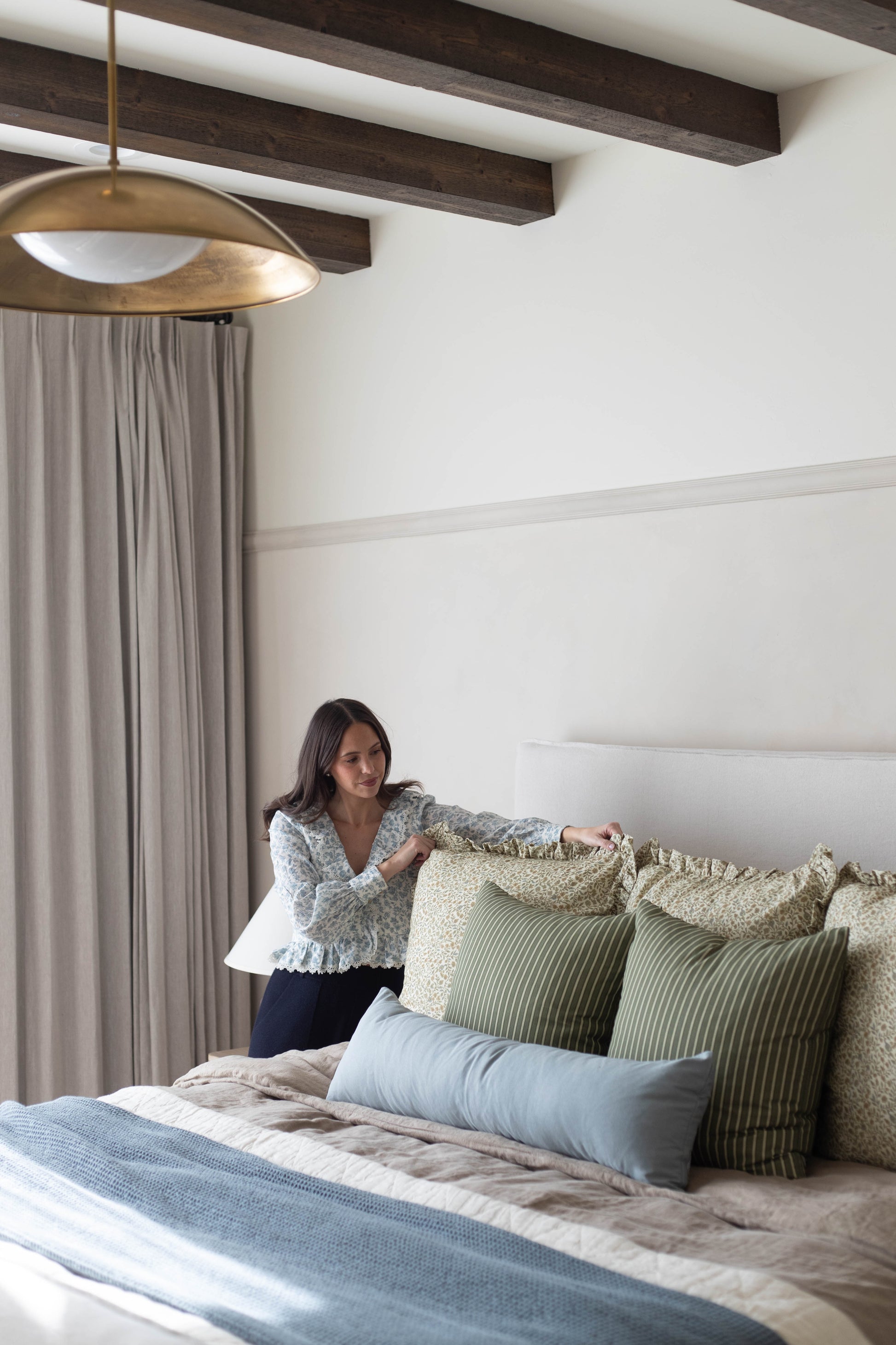 Dusty blue lumbar pillow displayed on a bed with coordinating patterned pillows and bedding.