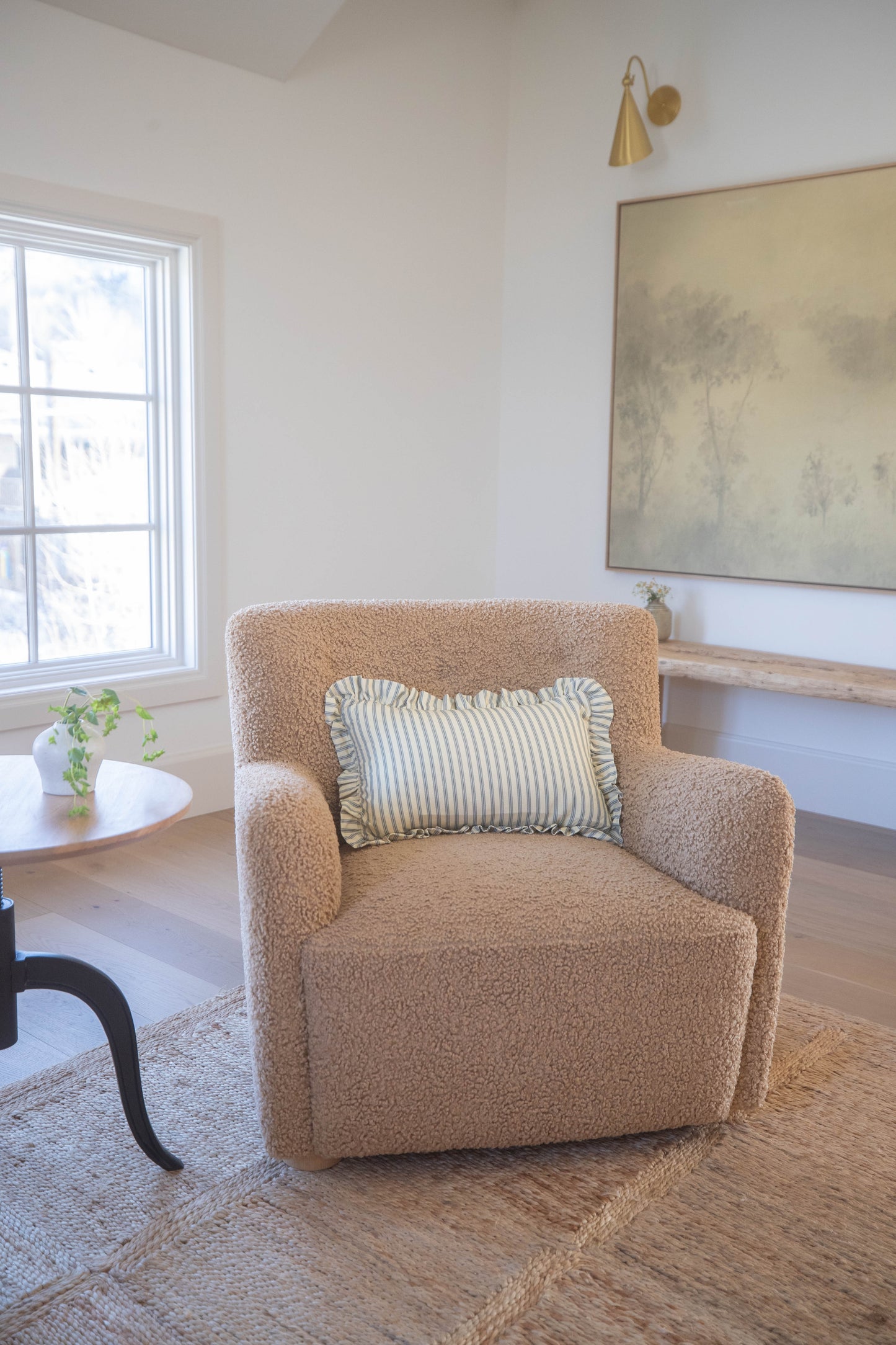 Ellis Ruffle lumbar pillow with striped sage and cream fabric and ruffled edges on beige upholstered chair.