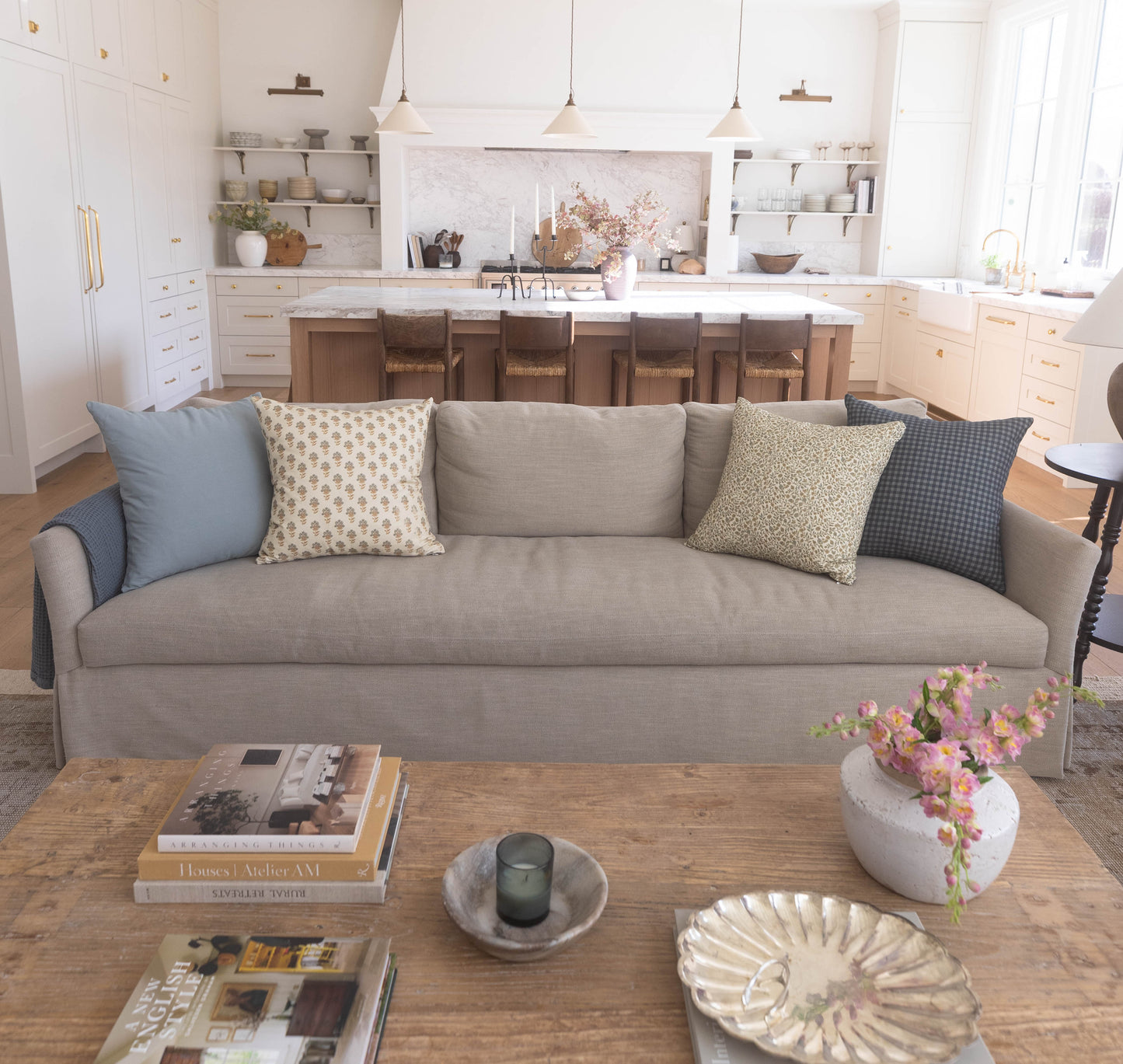 Four decorative pillows in blue, cream, beige, and gray patterns arranged on a gray upholstered sofa.