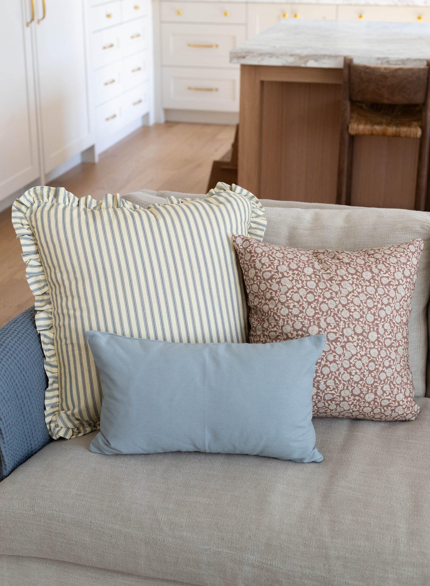 Light blue rectangular pillow with solid fabric displayed on a beige sofa with patterned pillows.