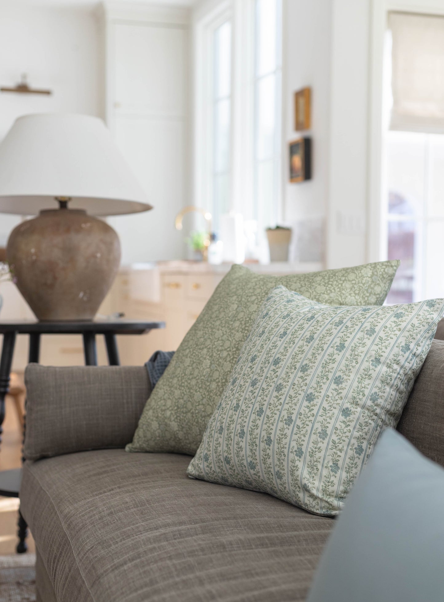 Green and cream patterned throw pillow with striped design on gray upholstered sofa.
