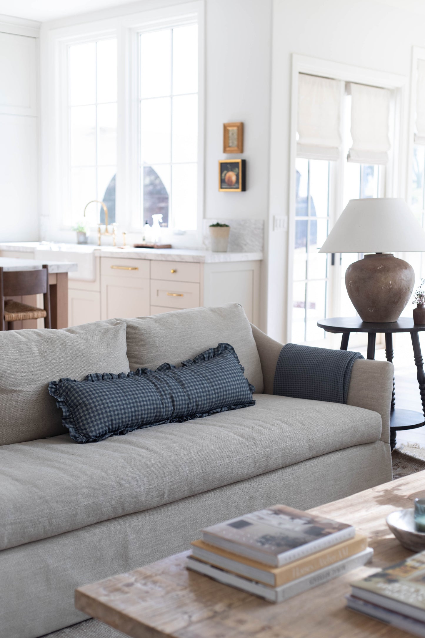 Navy gingham patterned pillow with ruffled edges displayed on a beige sofa.