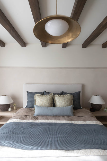 Navy and white gingham patterned pillow on bed with gold sequin and light blue pillows.