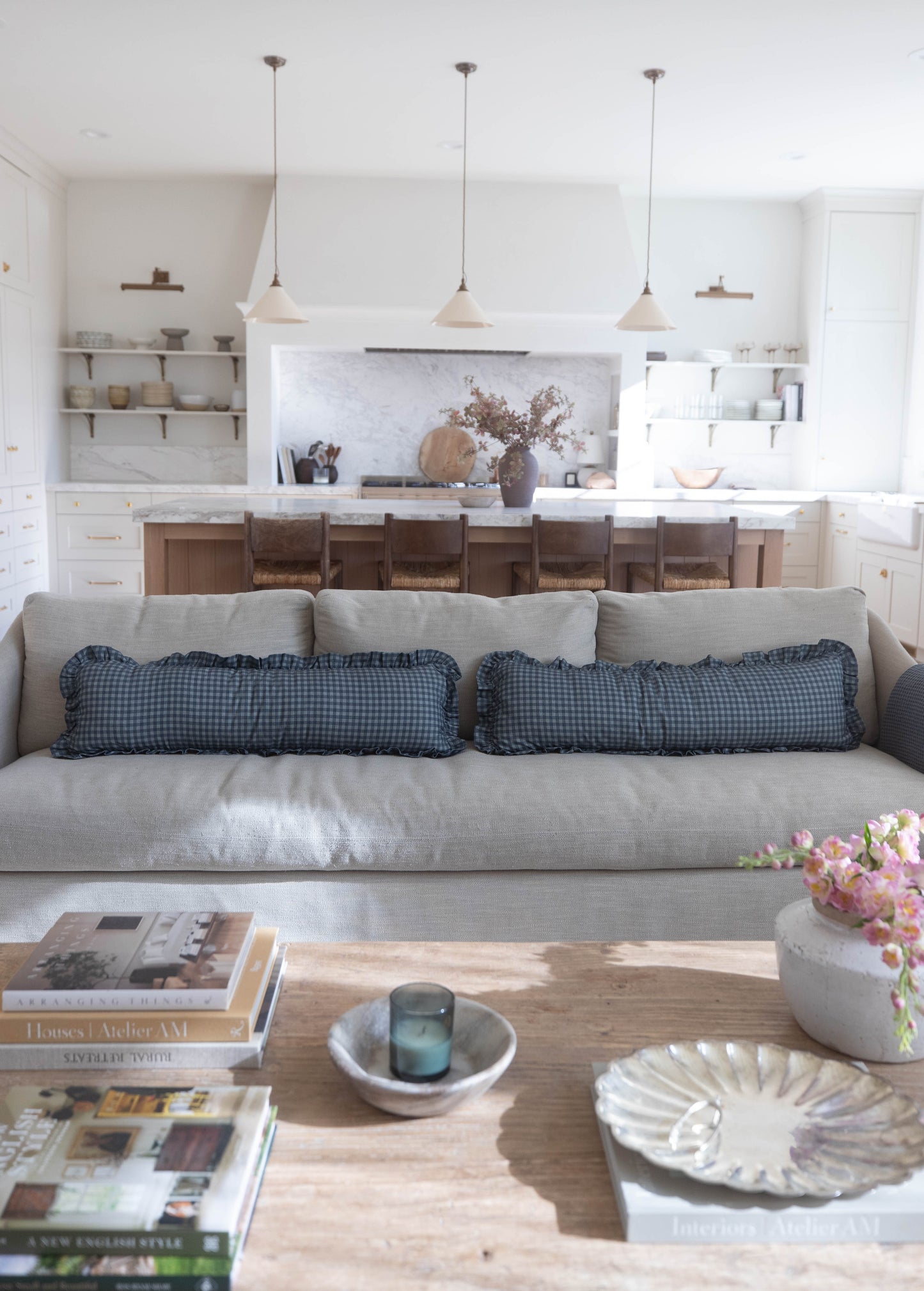 Navy gingham ruffle pillows with ruffled edges on gray sofa in living room.