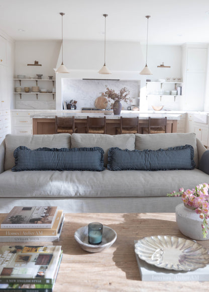 Navy gingham ruffle pillows with ruffled edges on gray sofa in living room.