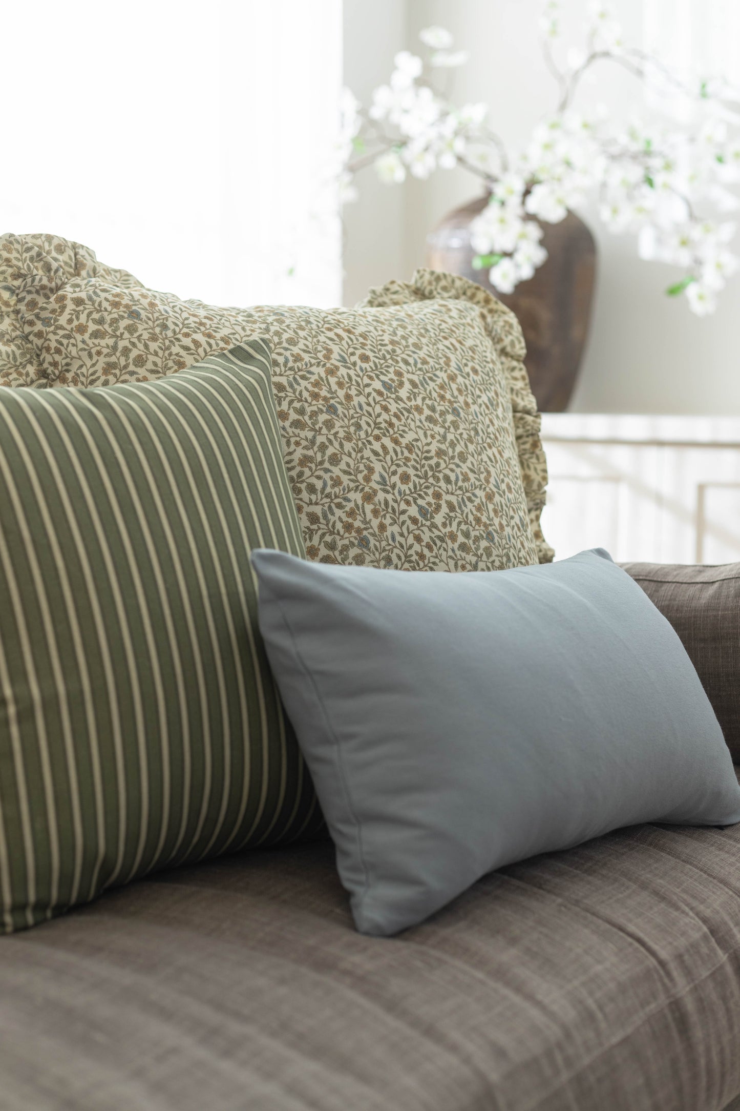 Blue rectangular pillow displayed on a gray sofa with patterned and striped accent pillows.