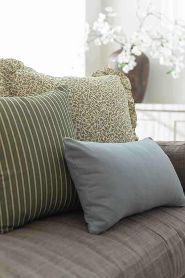 Blue rectangular pillow displayed on a gray sofa with patterned and striped accent pillows.