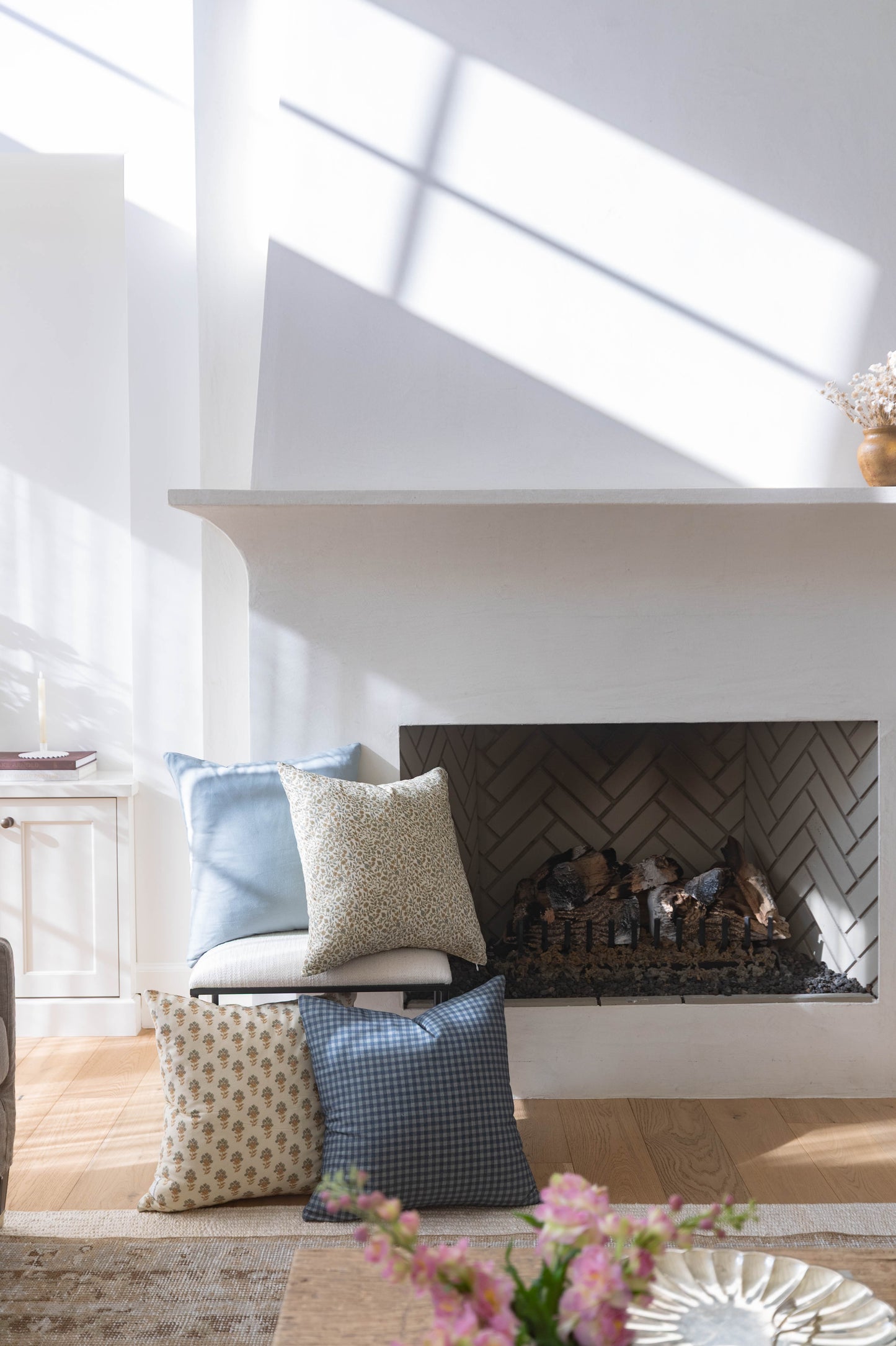 Navy and white gingham check pillow displayed on fireplace seating with coordinating patterned pillows.