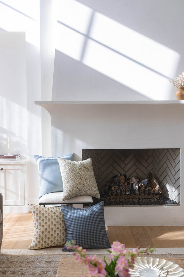 Navy and white gingham check pillow displayed on fireplace seating with coordinating patterned pillows.