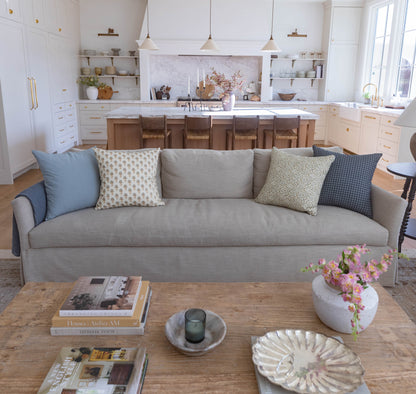 Navy gingham patterned throw pillow on gray sofa with coordinating solid and patterned accent pillows.