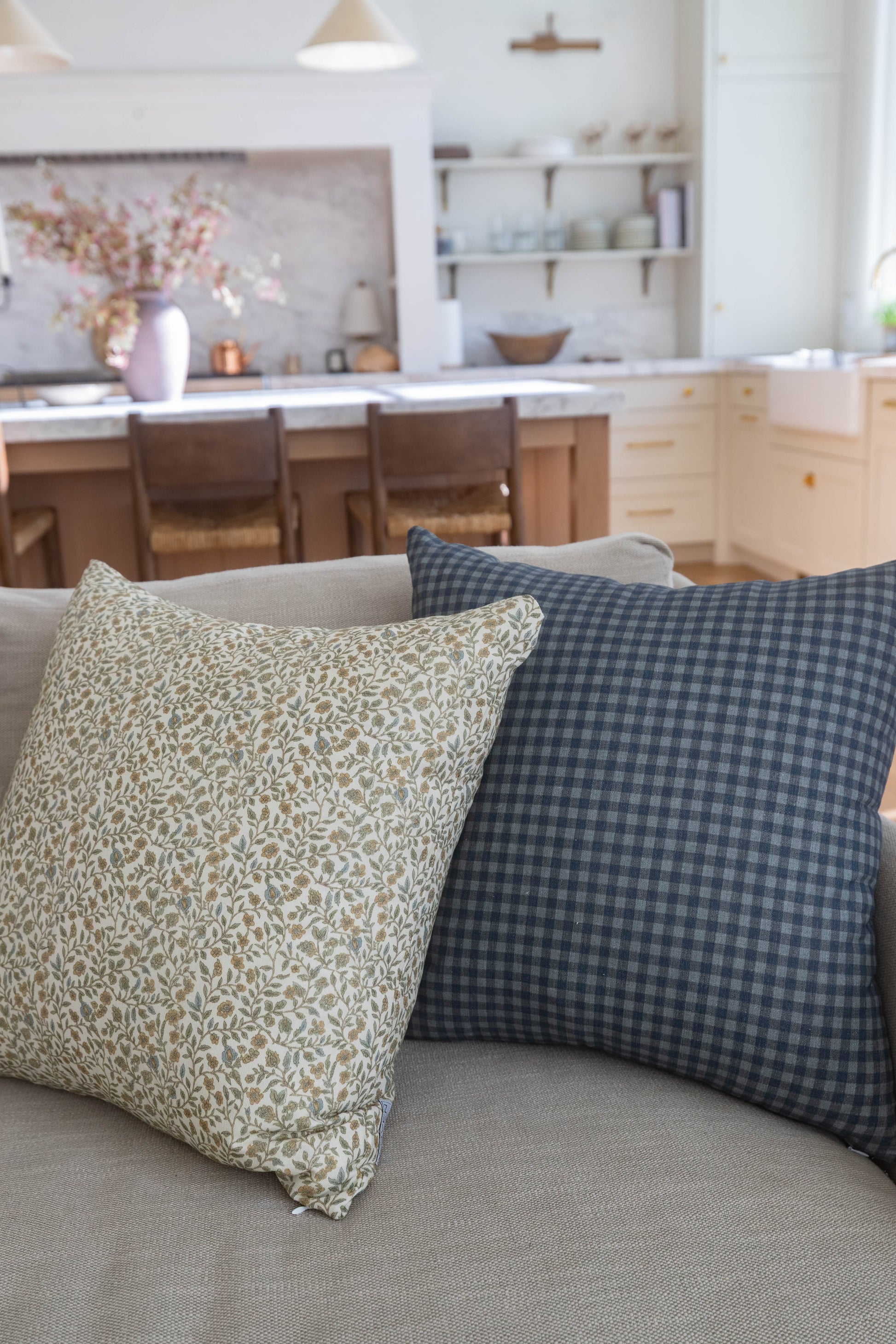 Navy gingham patterned pillow with small blue and white checks displayed on a beige sofa.