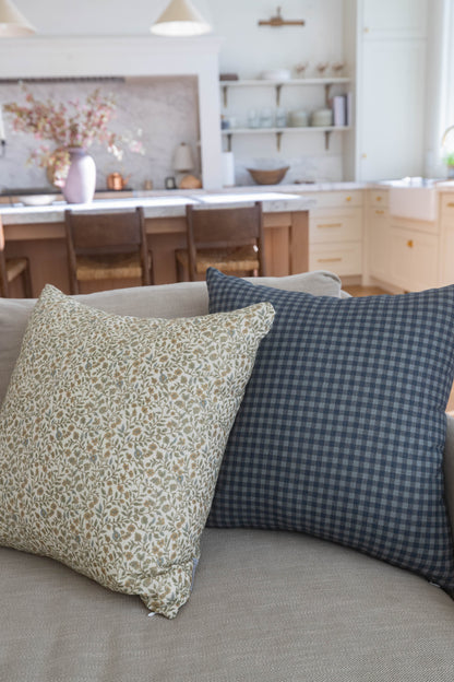 Navy gingham patterned pillow with small blue and white checks displayed on a beige sofa.