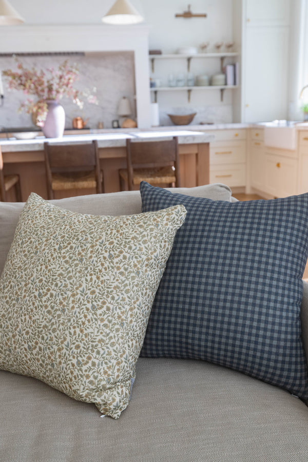 Navy gingham patterned pillow with small blue and white checks displayed on a beige sofa.