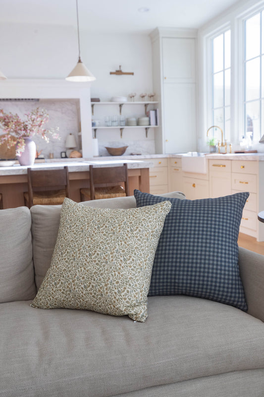 Navy gingham check pillow with small square pattern on gray sofa.