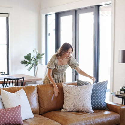 Tan and blue patterned throw pillow displayed on brown leather sofa with other decorative pillows.
