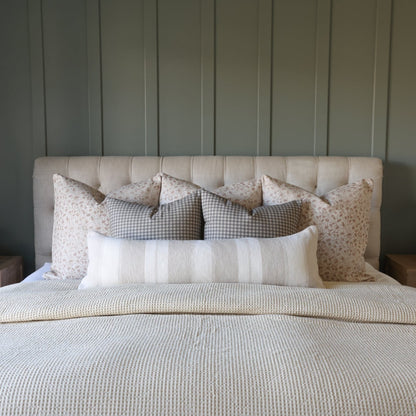 Brown and white gingham checkered pillows arranged on a bed with cream headboard and coordinating bedding.