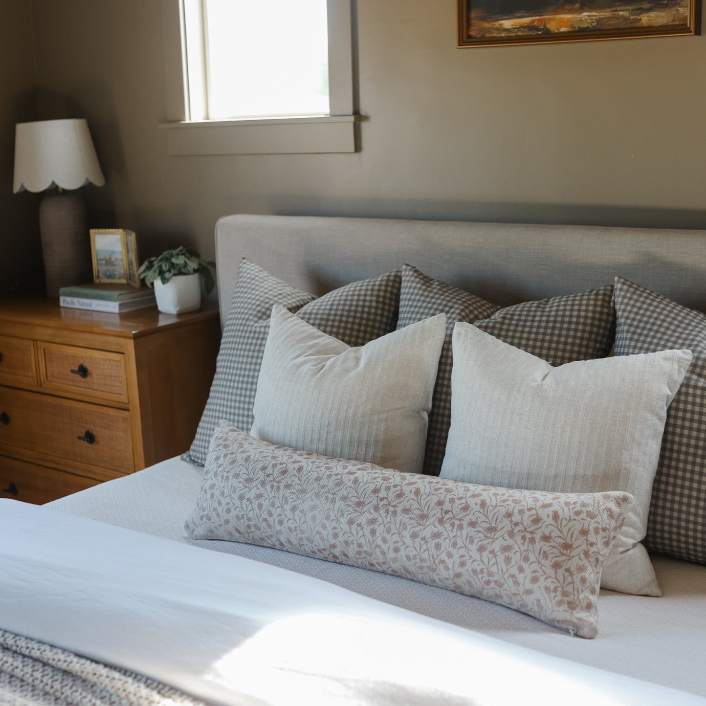 Brown and white gingham patterned pillows arranged on a bed with striped and floral accent pillows.