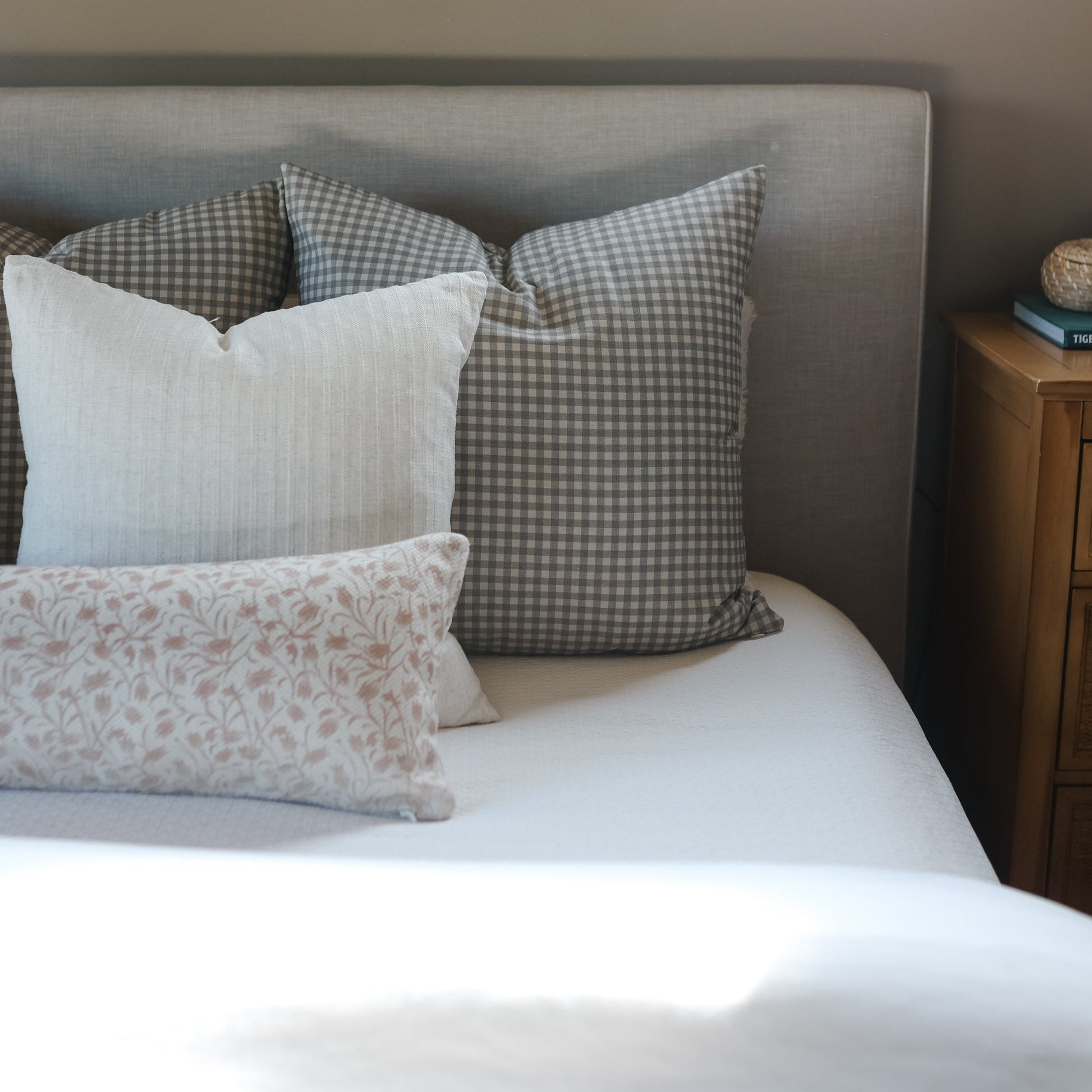 Brown and white gingham checkered throw pillows displayed on a bed with other decorative pillows.