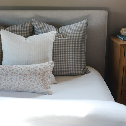 Brown and white gingham checkered throw pillows displayed on a bed with other decorative pillows.