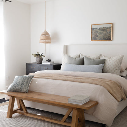 Woven pendant light with natural rattan shade hanging above bedroom nightstand.