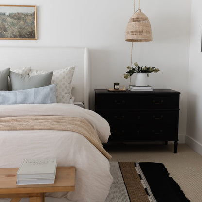 Woven pendant light with teardrop shape and natural rattan finish, hanging above bedroom nightstand.