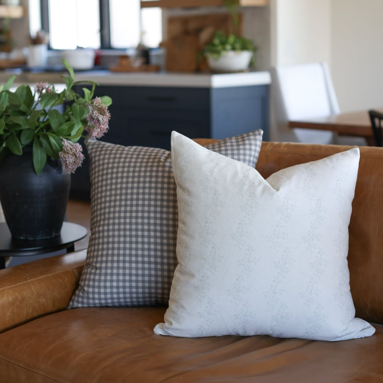 Brown and white gingham check pillow cover displayed on a leather sofa.