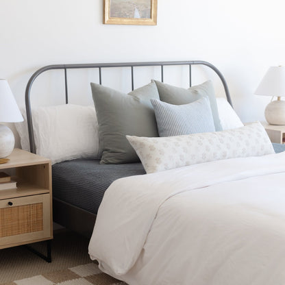 Lyla lumbar pillow in light floral pattern displayed on bed with gray headboard and neutral bedding.