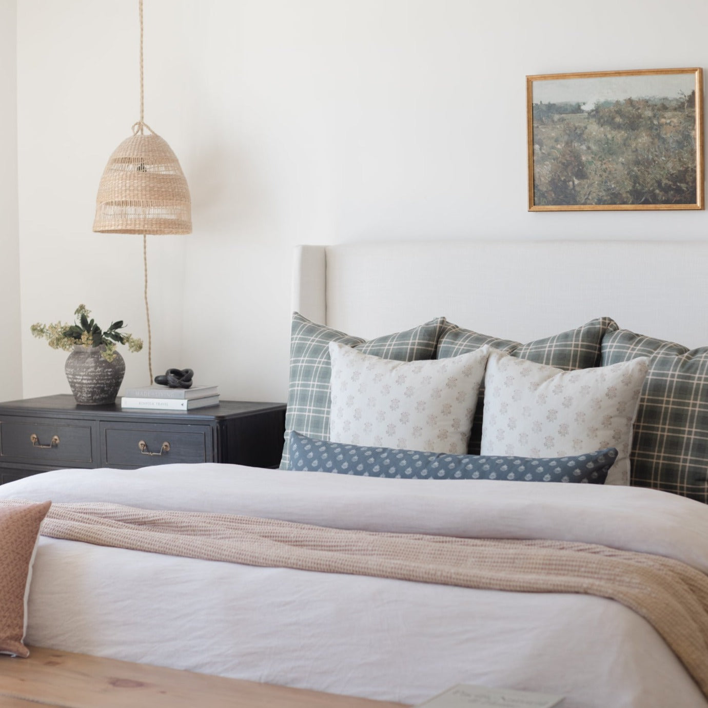 Woven pendant lamp with dome shape in natural rattan finish, suspended by cord over bedside table.