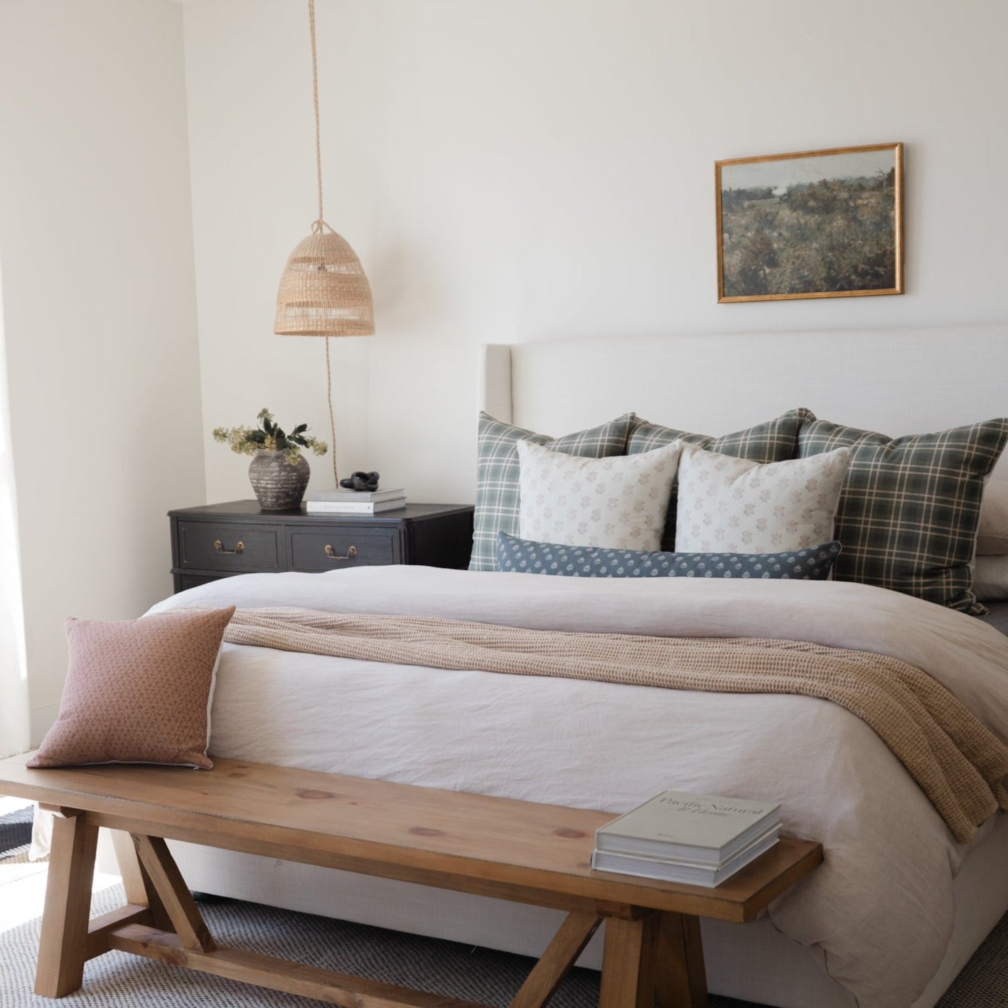 Woven pendant light in natural rattan material hanging above bedroom nightstand.