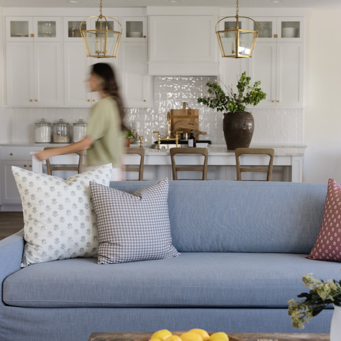 Blue upholstered sofa with decorative pillows in a modern kitchen and dining room setting.