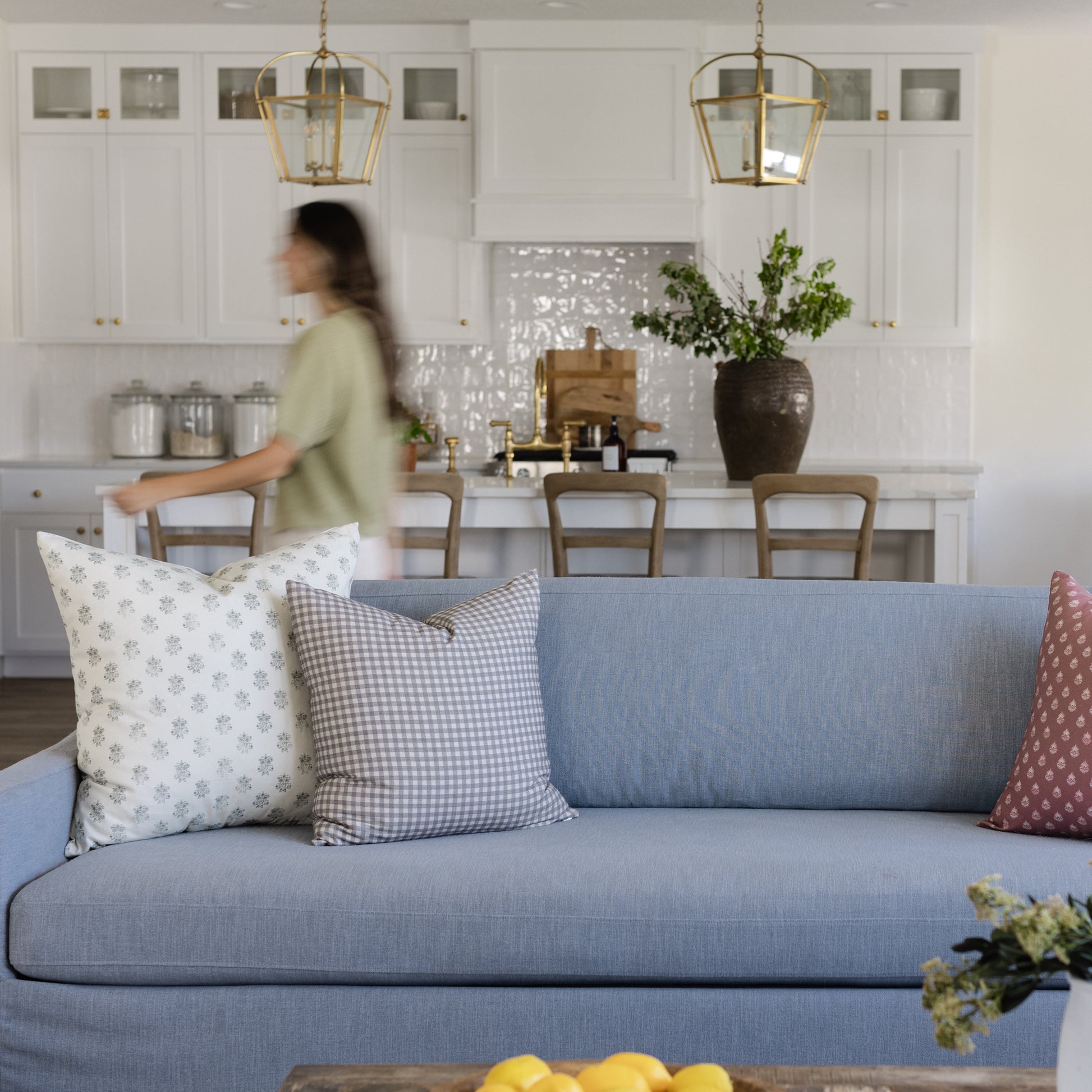 Blue upholstered sofa with decorative pillows in a modern kitchen and dining room setting.