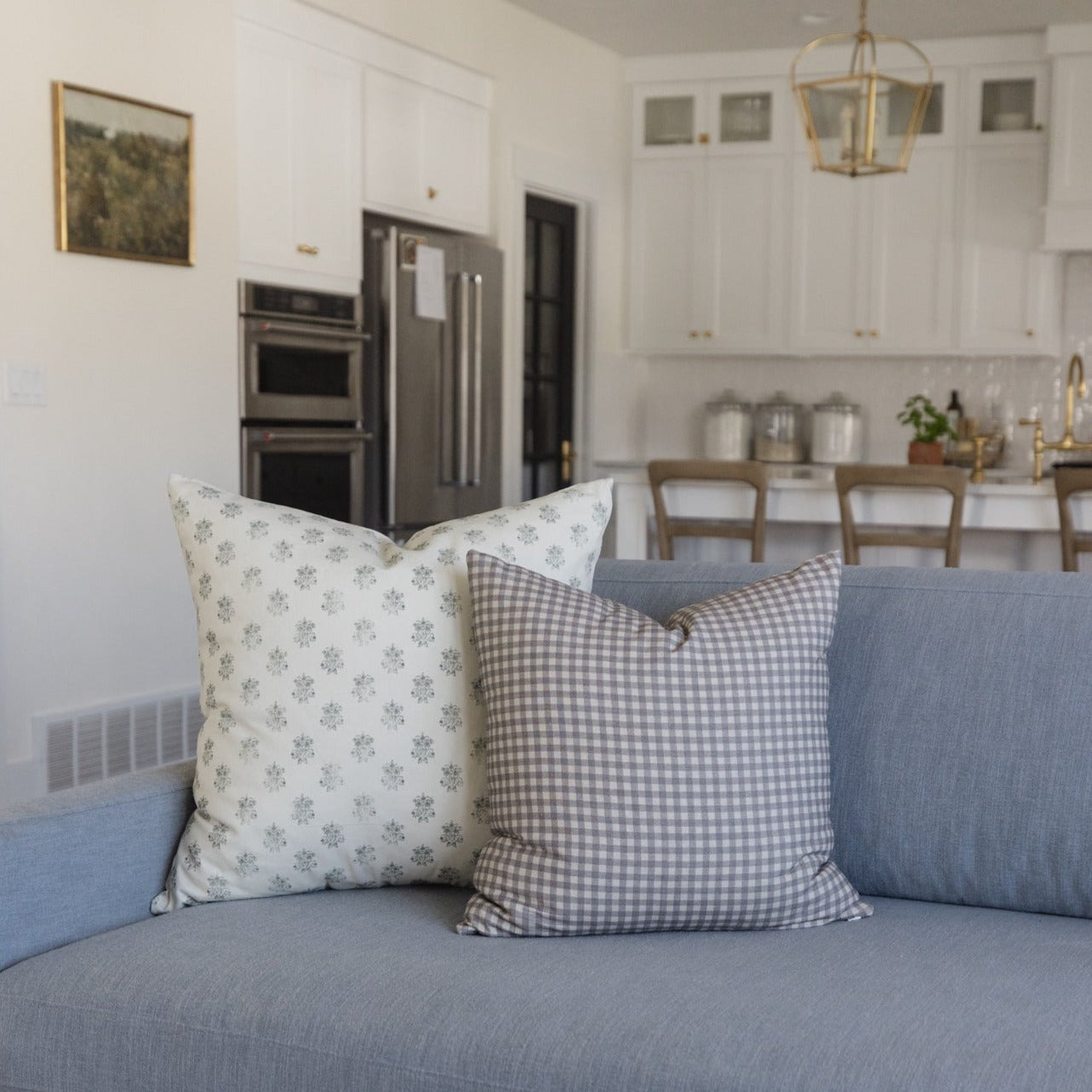Blue upholstered sofa with decorative pillows in floral and gingham patterns.