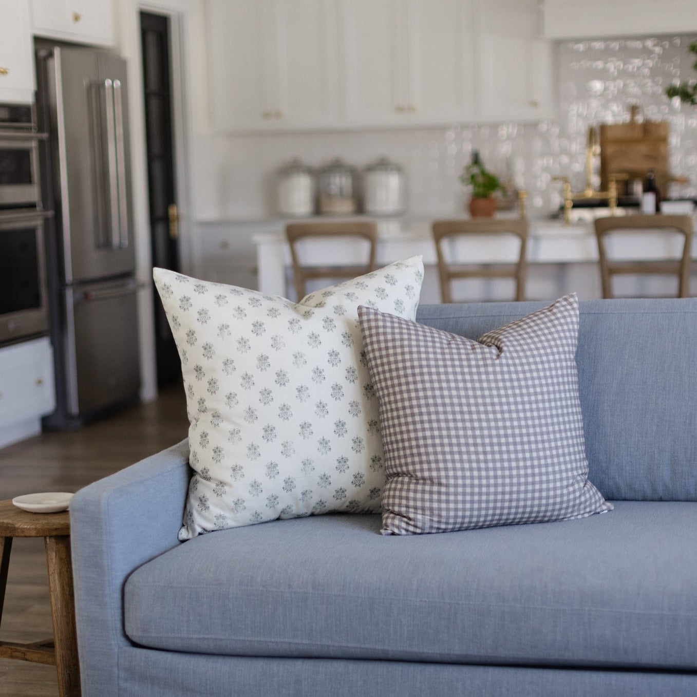 Blue upholstered sofa with decorative pillows in a kitchen-dining room setting.