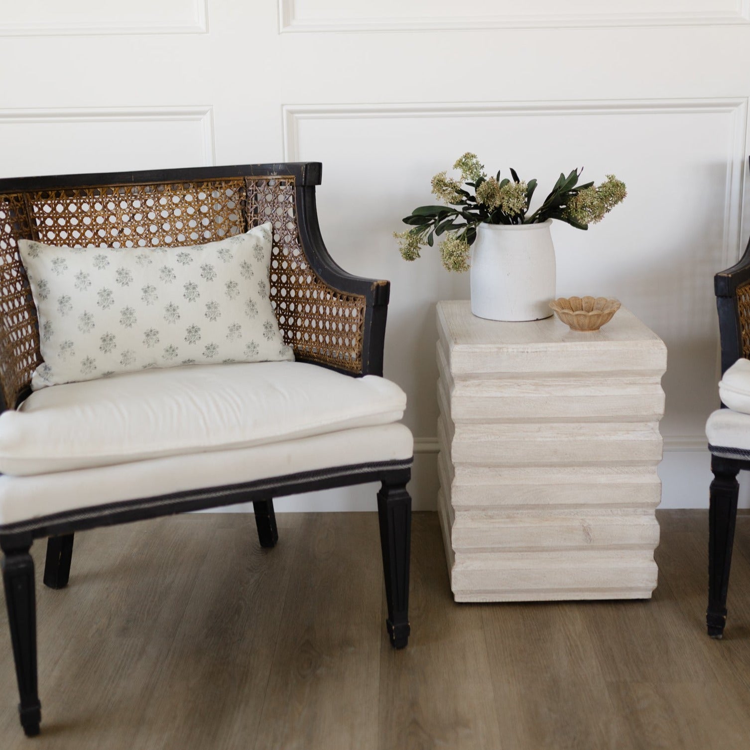 Blue upholstered chair with woven rattan back and black frame, displayed in a styled living room setting.