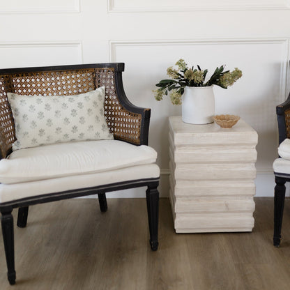 Blue upholstered chair with woven rattan back and black frame, displayed in a styled living room setting.