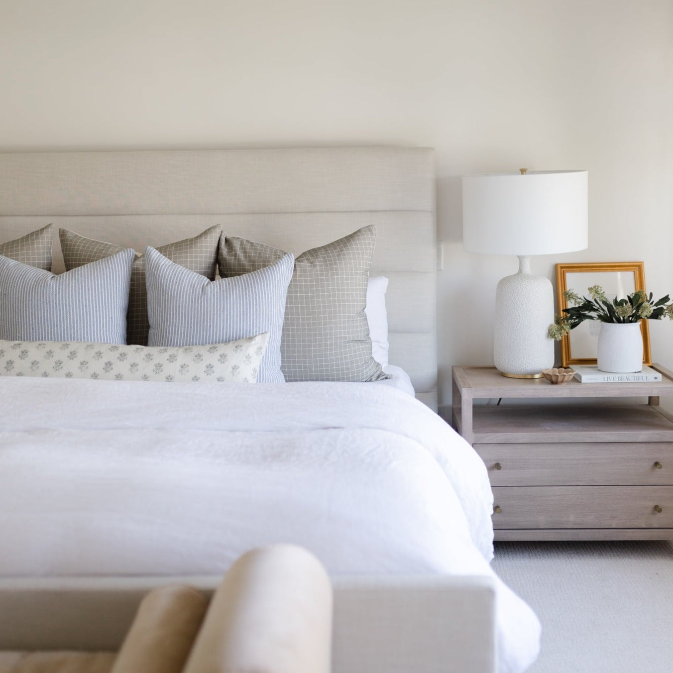 Blue striped decorative pillow displayed on a bed with coordinating patterned pillows and white bedding.