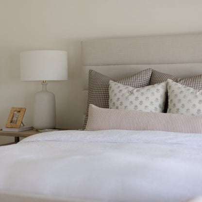 Blue Lyla pillow with small-scale pattern displayed on bed with checkered and striped pillows.