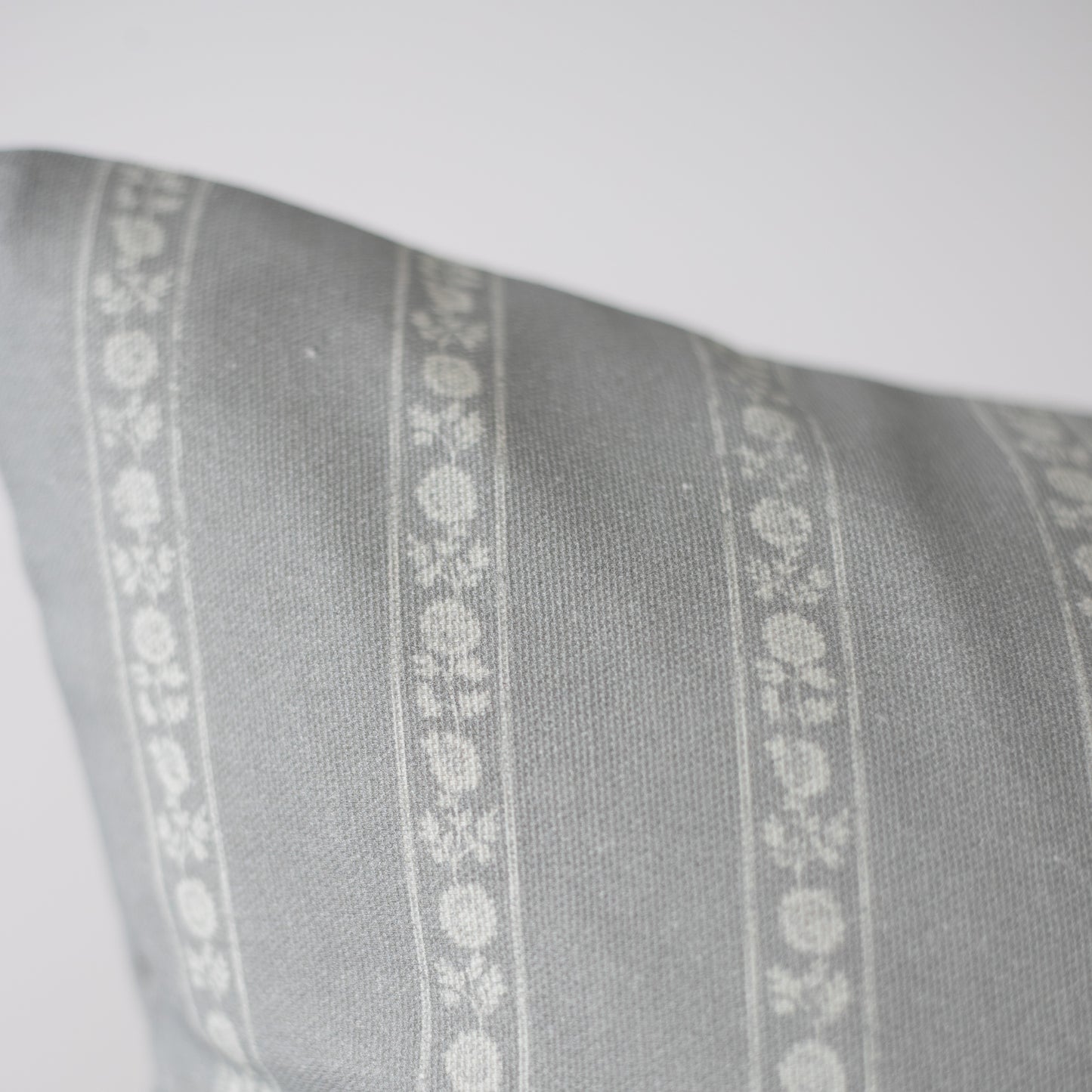 Gray pillow with white floral stripe pattern running vertically down the center.