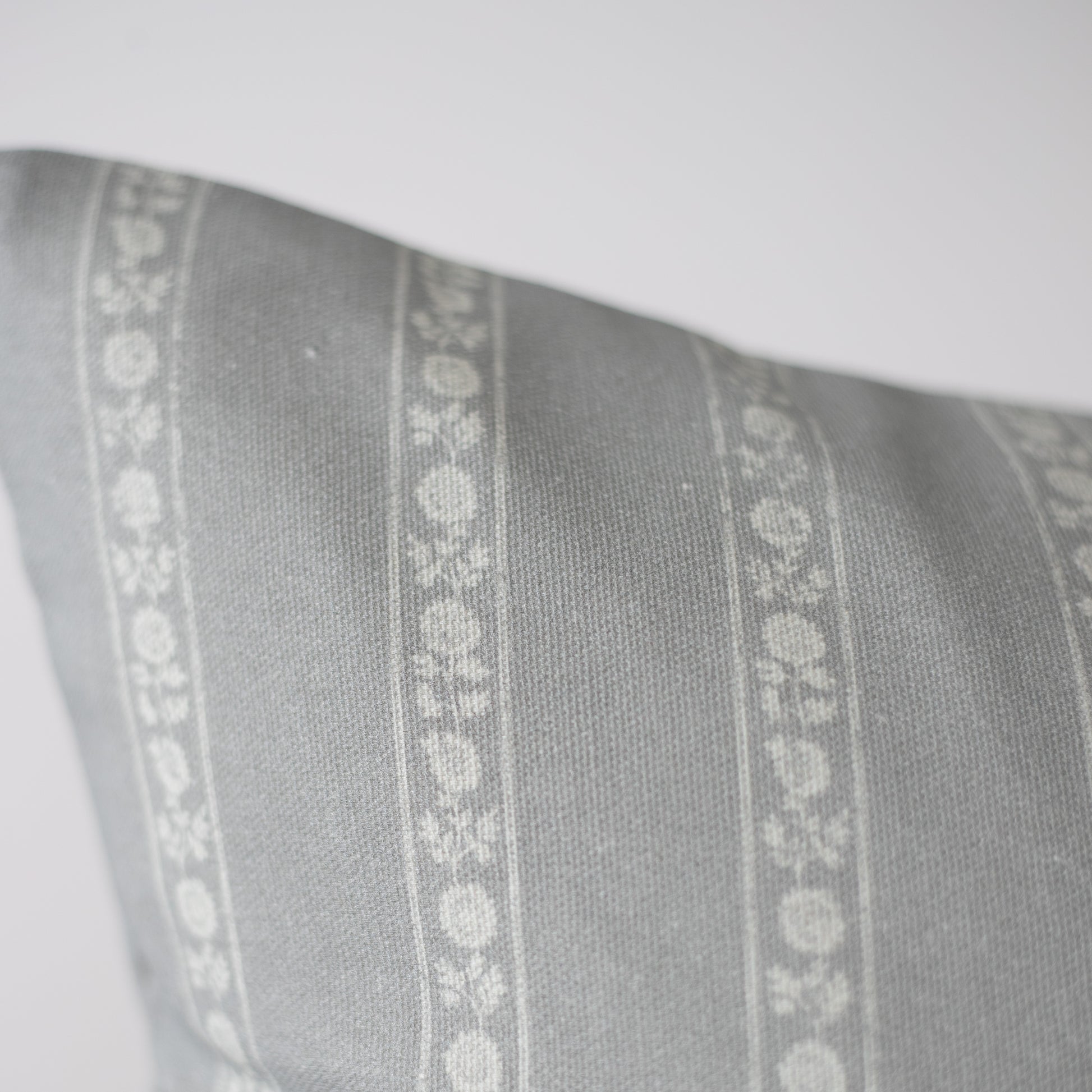 Gray pillow with white floral stripe pattern running vertically down the center.